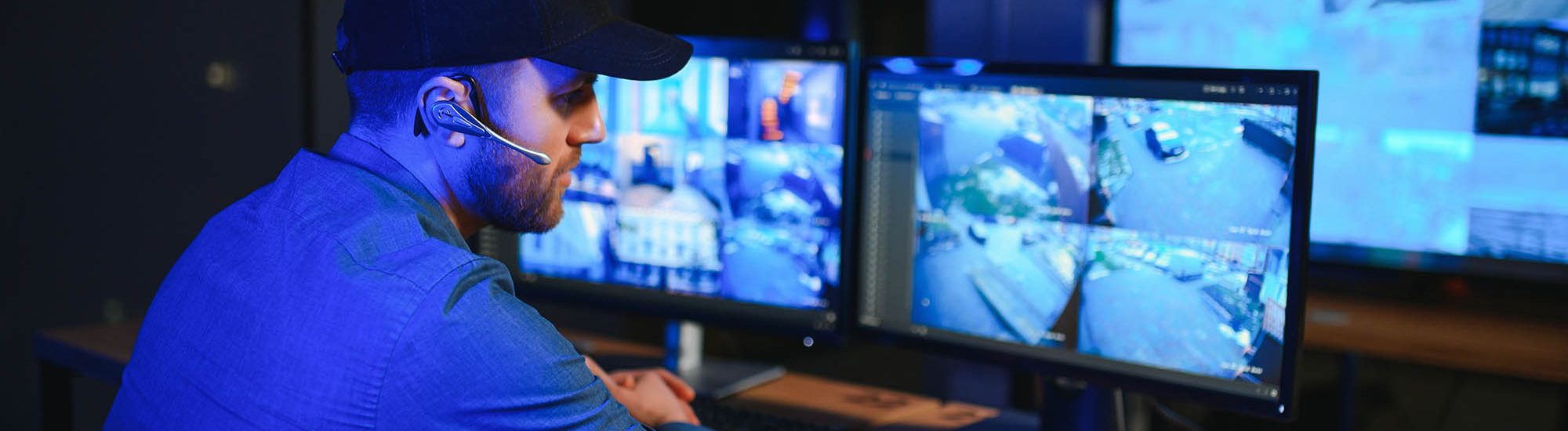 Male security guard monitoring modern CCTV cameras indoors.