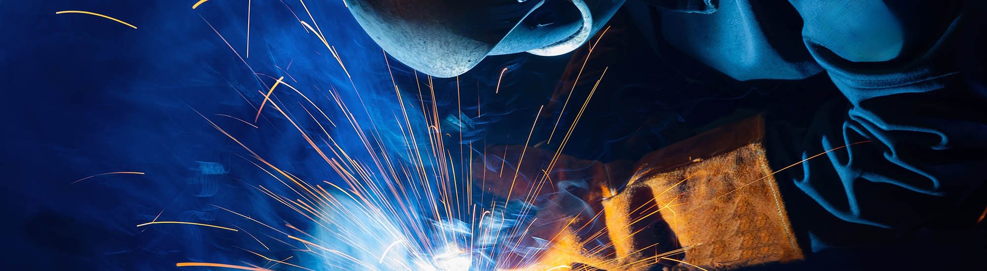 Factory industrial welder worker in workplace with spark, neon light. Professional welder fix industry truck.