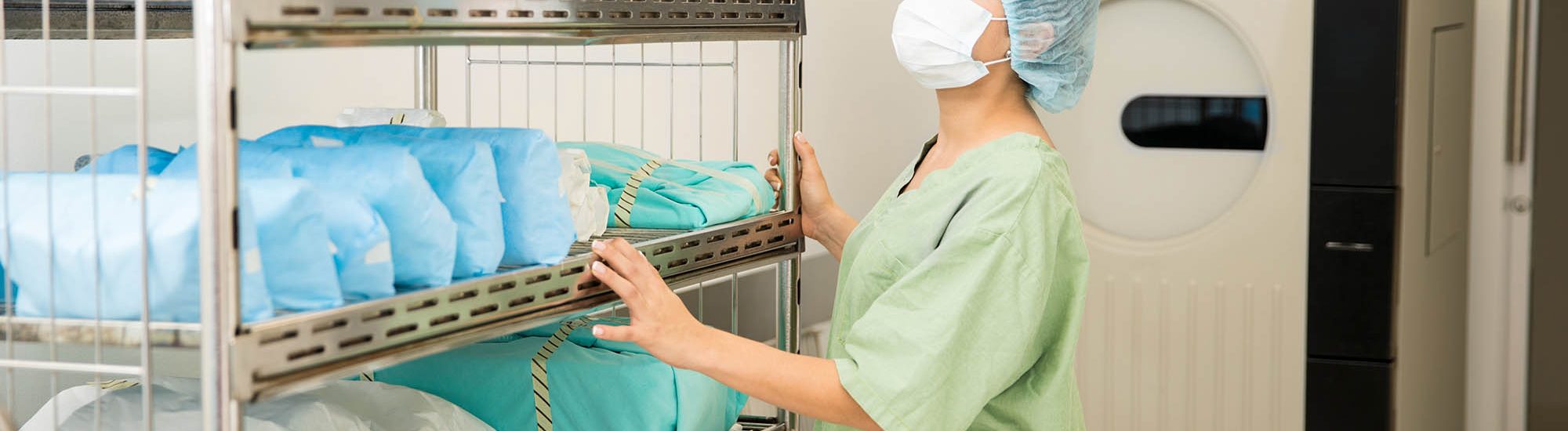 Cute young woman in scrubs looking at a cart full of clean and sterile clothing in a hospital